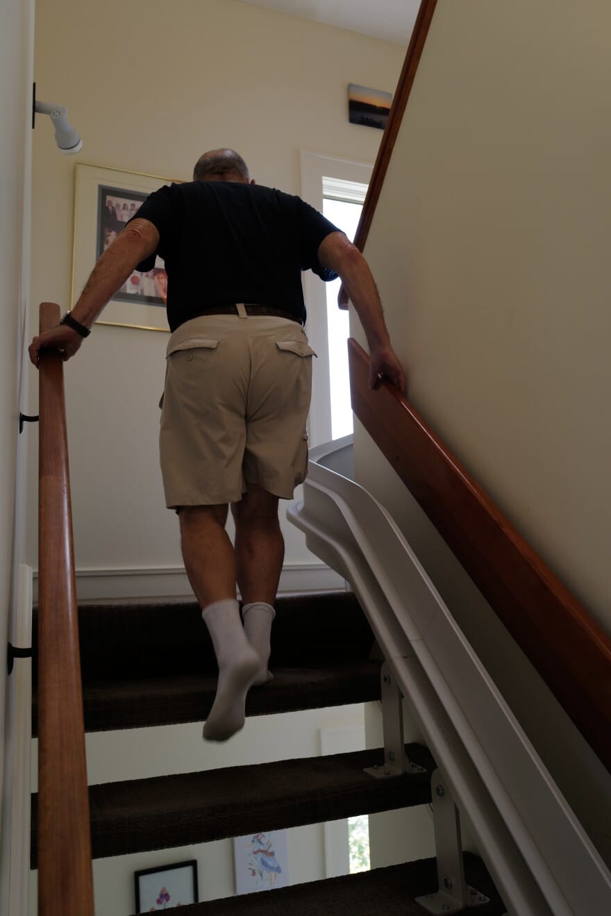Howard Weinberg goes upstairs at his Virginia Beach home, using both hands on the banisters he installed to help prevent falls.