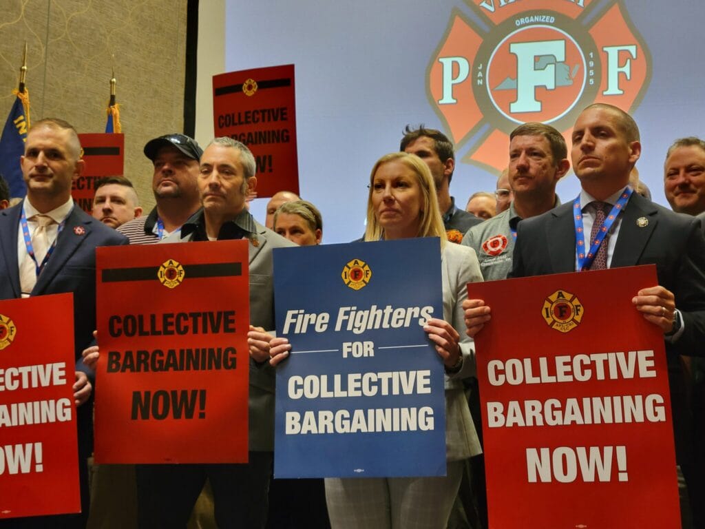 Members of Virginia Professional Firefighters association hold signs during their biannual convention in May to protest Democratic Gov. Abigail Spanberger’s veto of collective bargaining legislation. New research found a significant spike in labor union membership, but growth is highly dependent upon state politics. (Photo by Charlotte Rene Woods/Virginia Mercury)