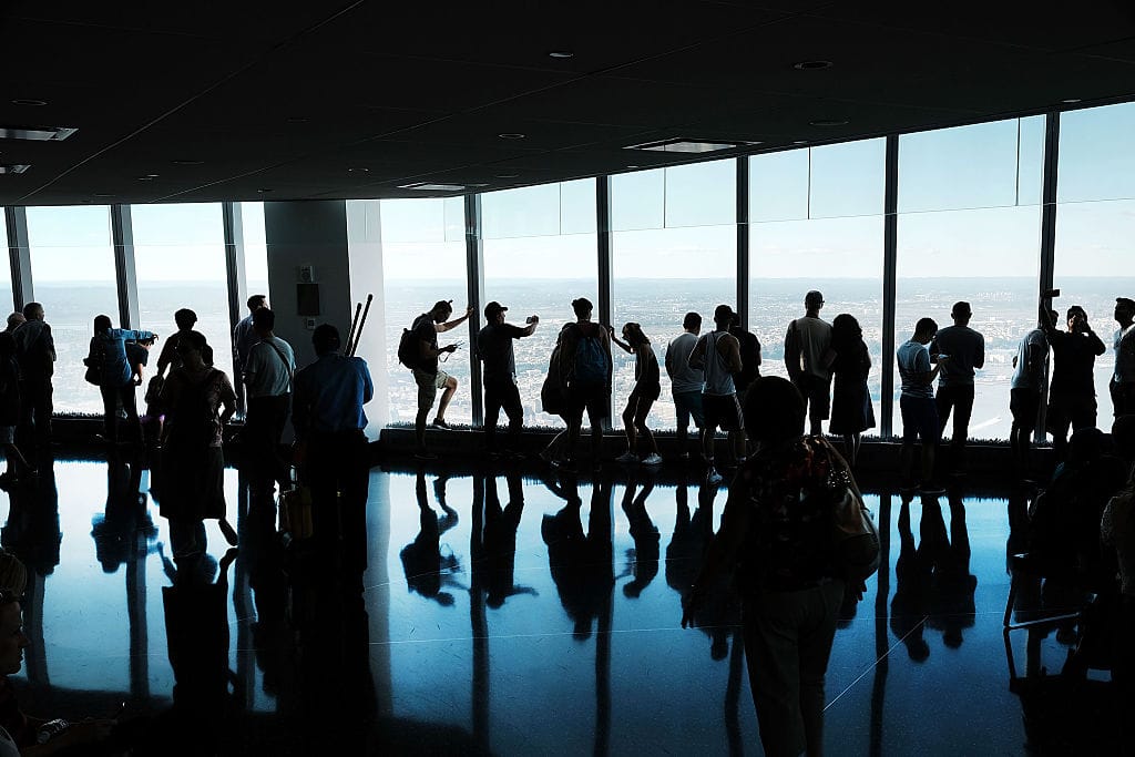 People look out at Manhattan and beyond at One World Observatory at One World Trade Center in New York City. Twenty-five years after 9/11, the surveillance systems built in its aftermath continue to shape how Americans are watched and policed. (Photo by Spencer Platt/Getty Images)